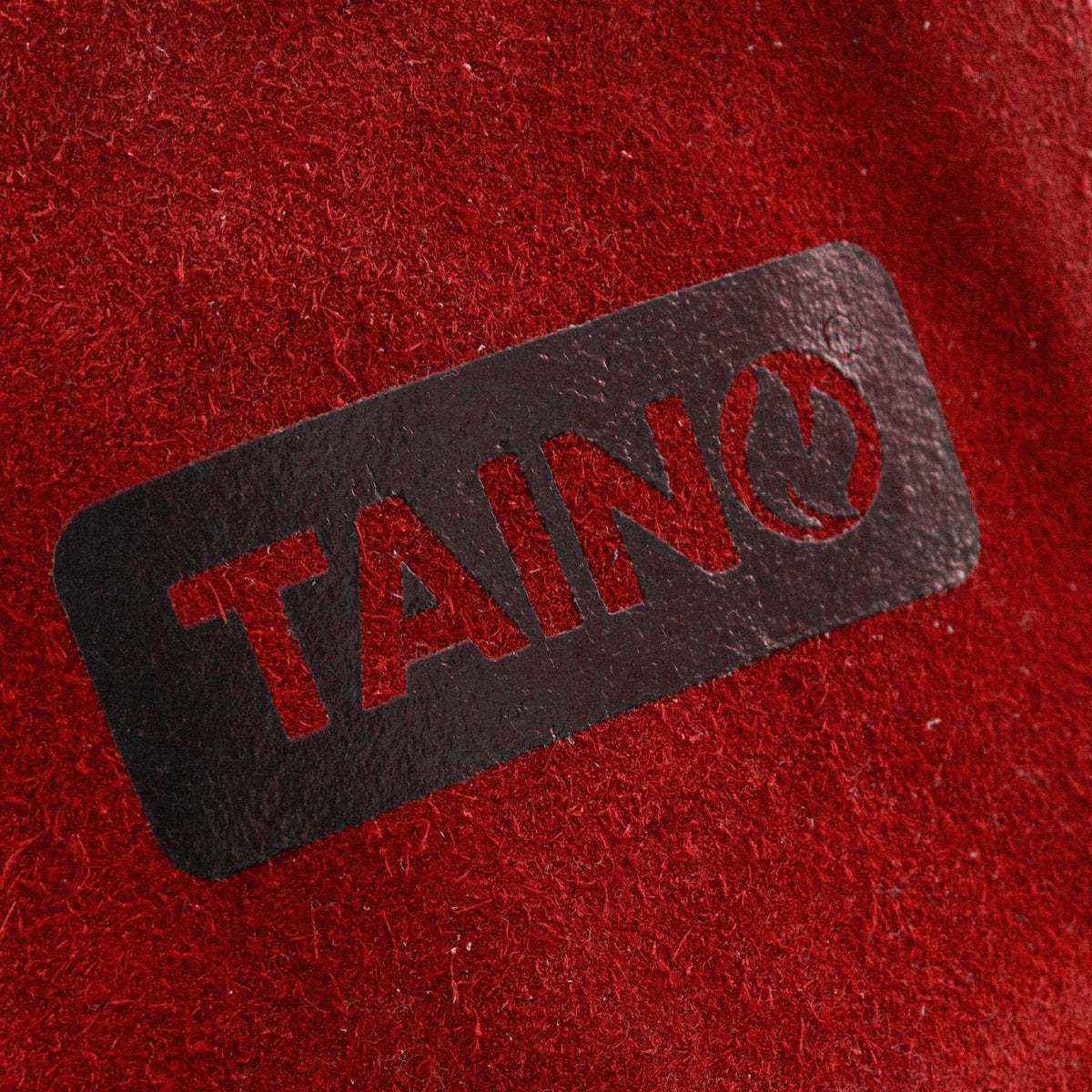 Nahaufnahme des schwarzen TAINO-Logos auf dem roten Leder